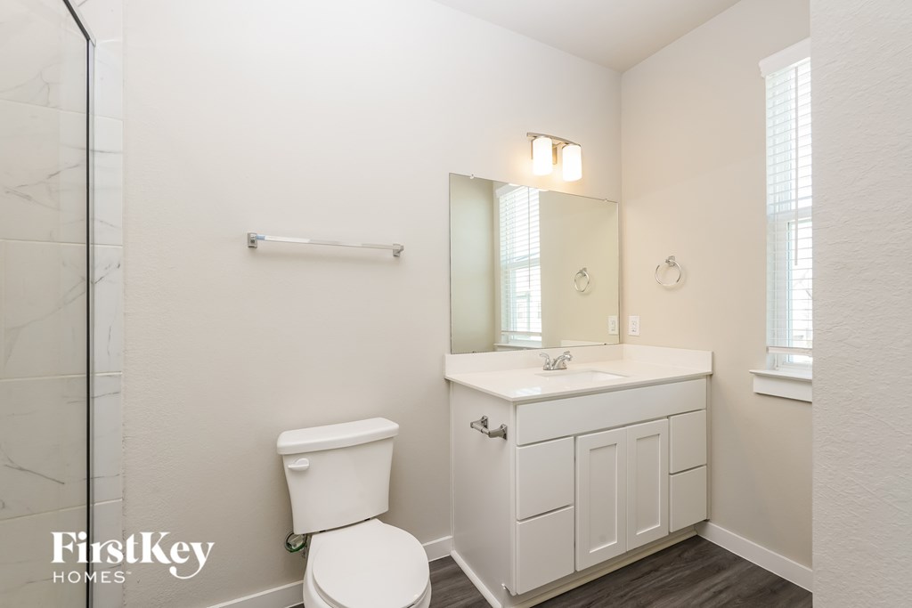 A white toilet sits in a small bathroom with a white sink and a mirror.