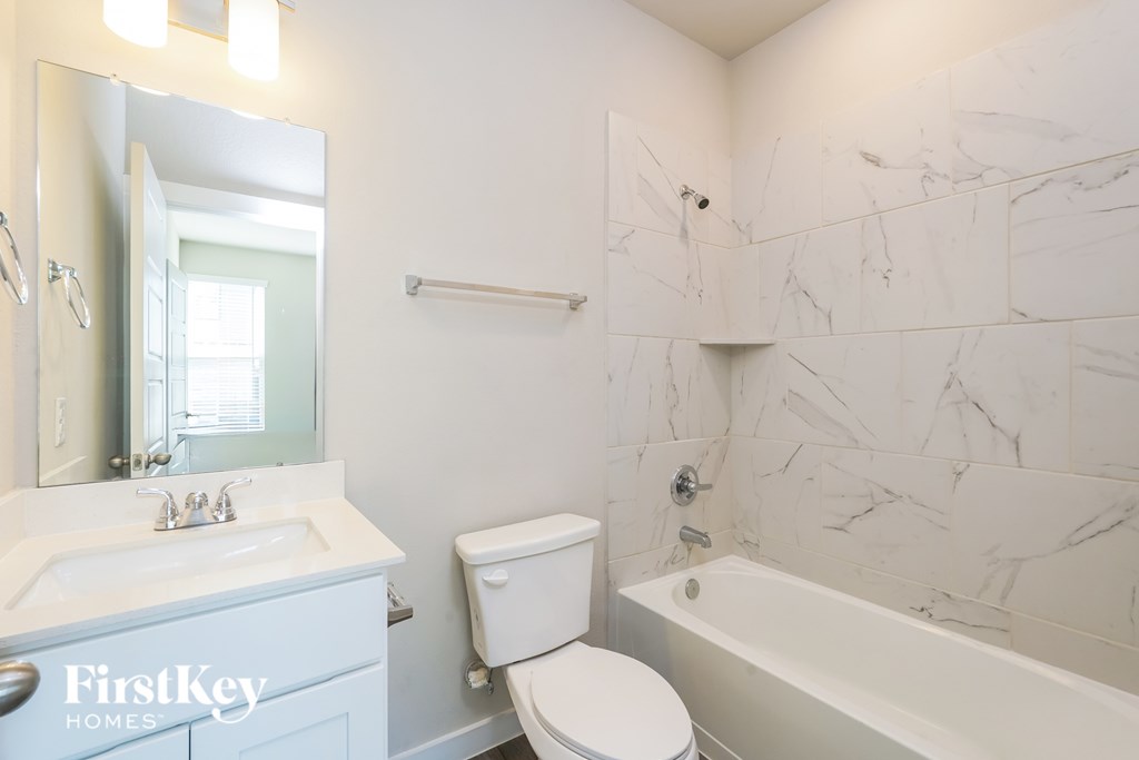 A white bathroom with a marble wall and a white toilet.