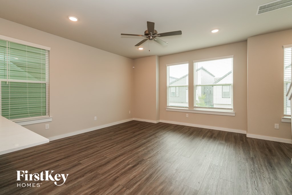 A spacious room with wooden flooring and a ceiling fan.