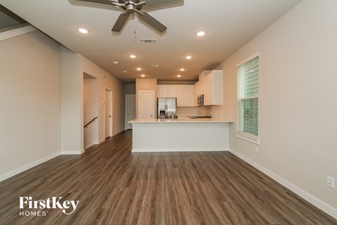 A spacious kitchen with wooden floors and a ceiling fan.