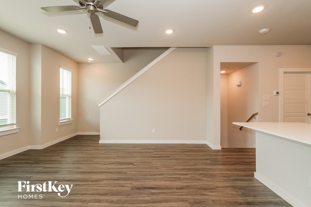 A spacious room with a ceiling fan and wooden flooring.