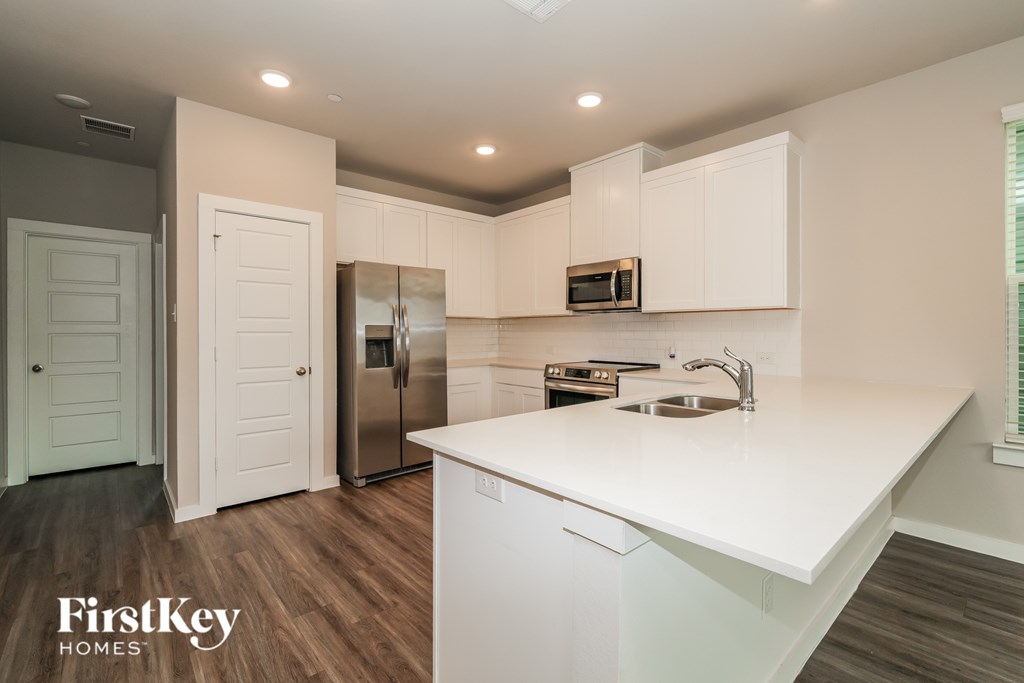 A kitchen with white countertops and wooden floors.