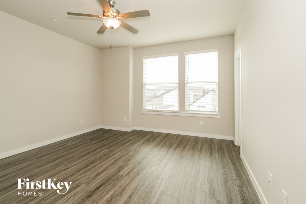 A room with a ceiling fan and wooden flooring.