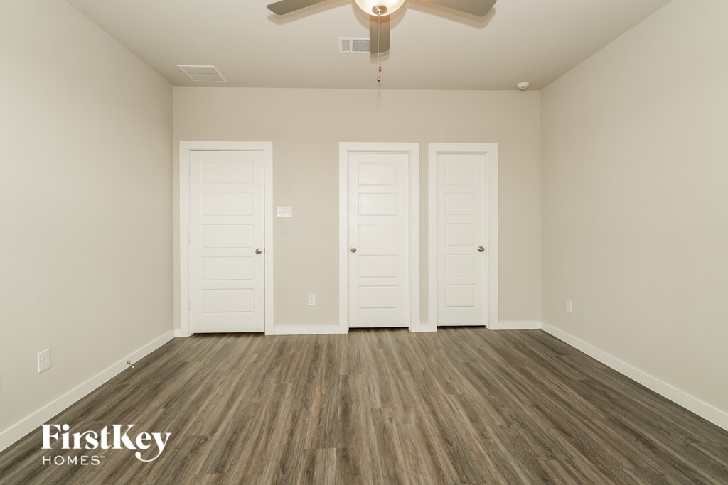 A room with wooden floors and three white doors.