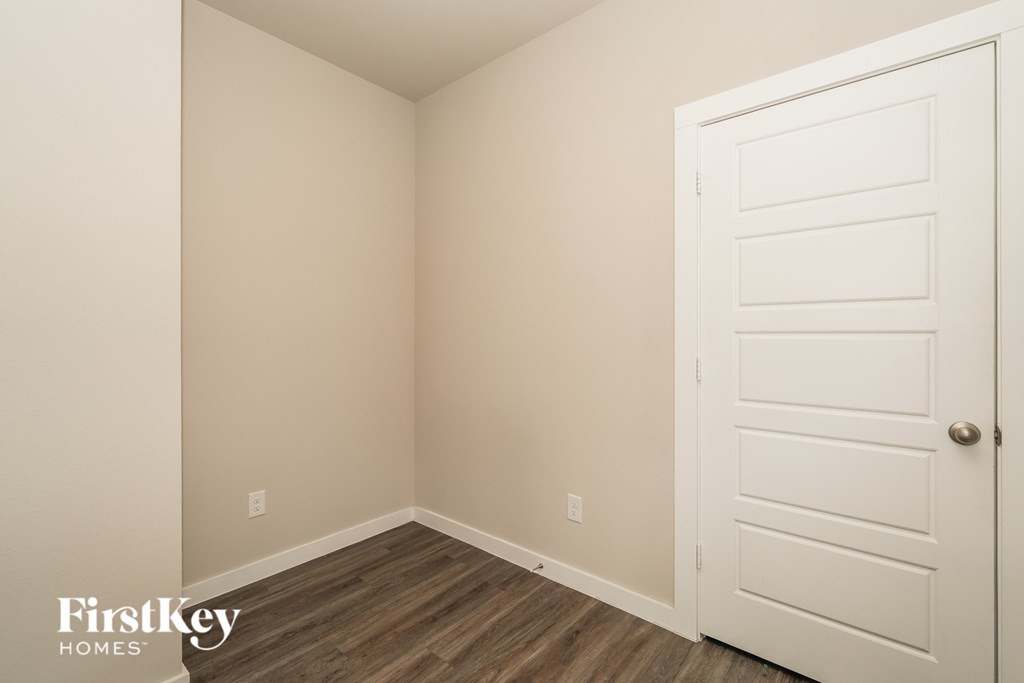 A room with a white door and wooden floor.