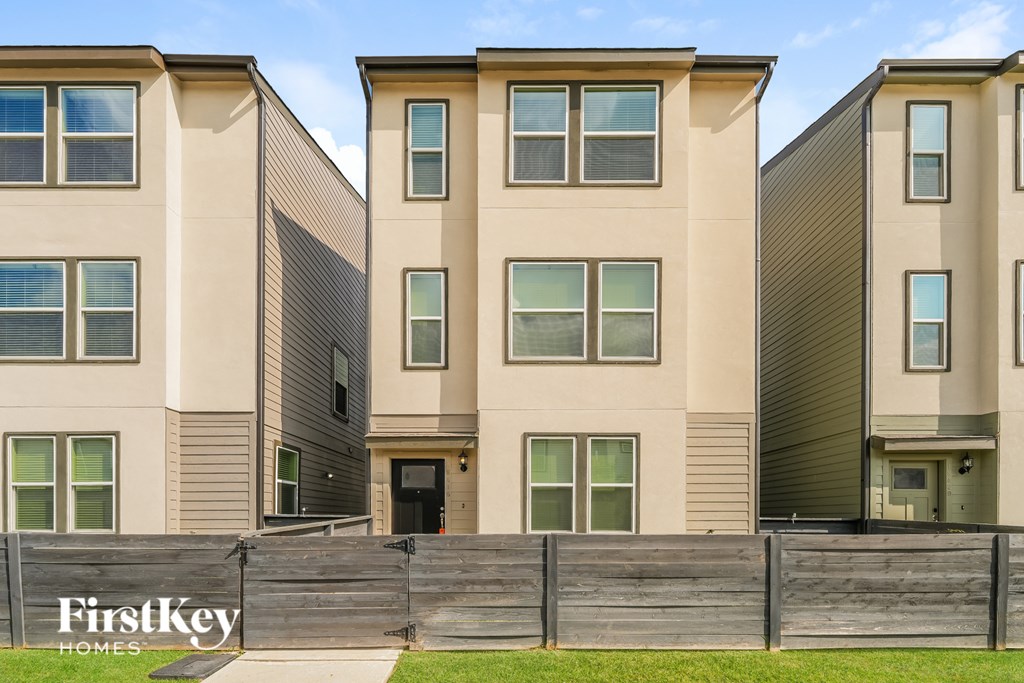 A row of modern townhouses with a fence in front.