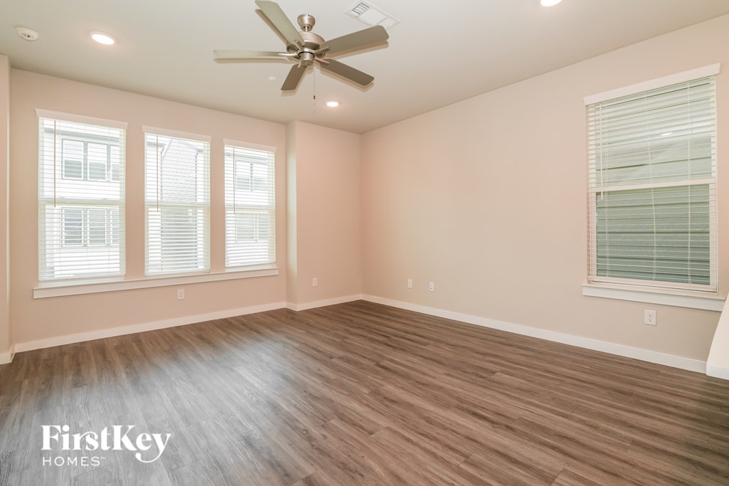 A room with a ceiling fan and wooden flooring.