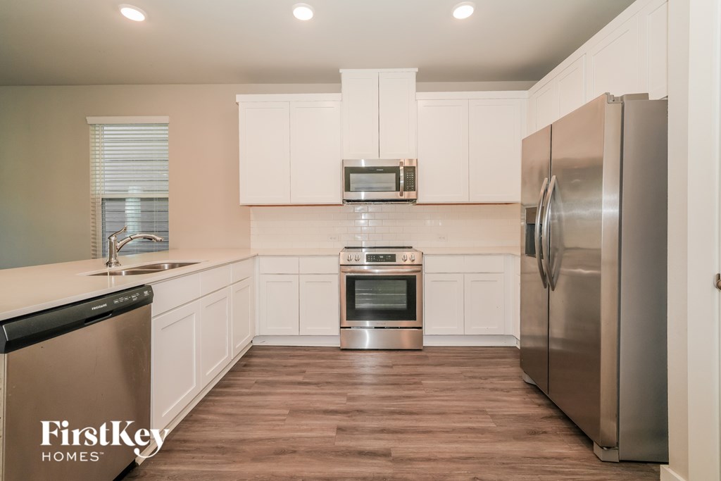 A kitchen with stainless steel appliances and wooden floors.