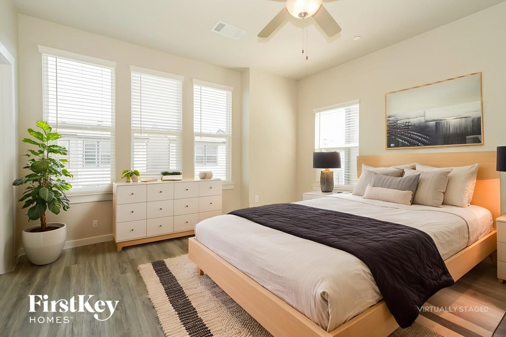 A bedroom with a large bed, a dresser, and a plant.