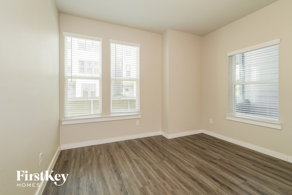 A room with wooden floors and two windows.