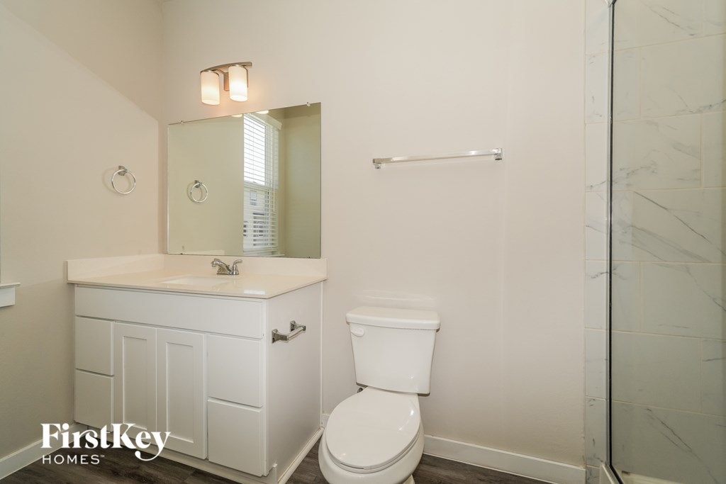 A white toilet in a bathroom with a mirror and a towel bar.