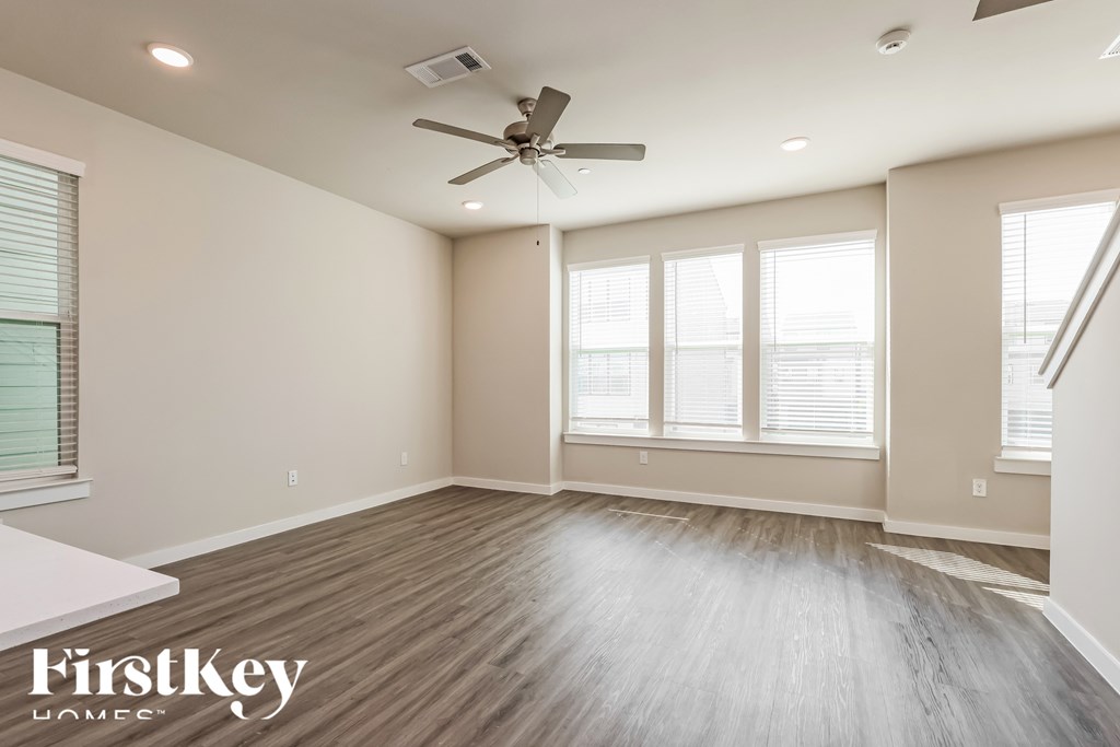 A spacious room with a ceiling fan and wooden flooring.