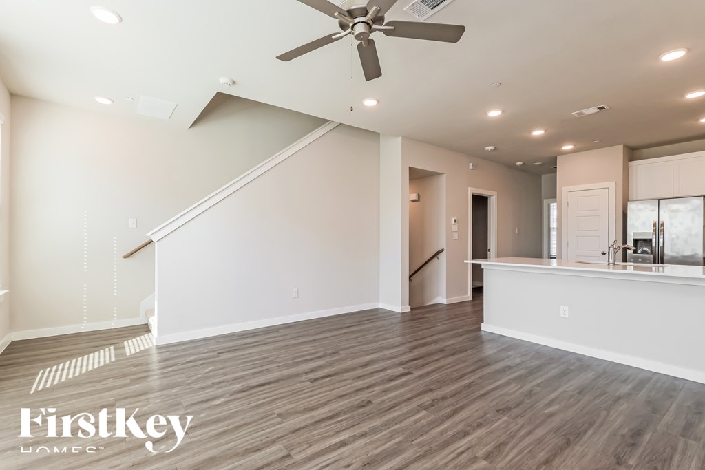 A spacious room with a wood floor and a ceiling fan.