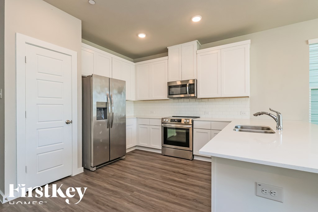 A kitchen with white cabinets and a stainless steel refrigerator.