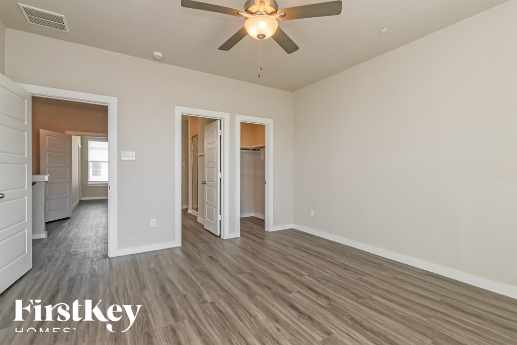 A spacious room with a ceiling fan and wooden flooring.