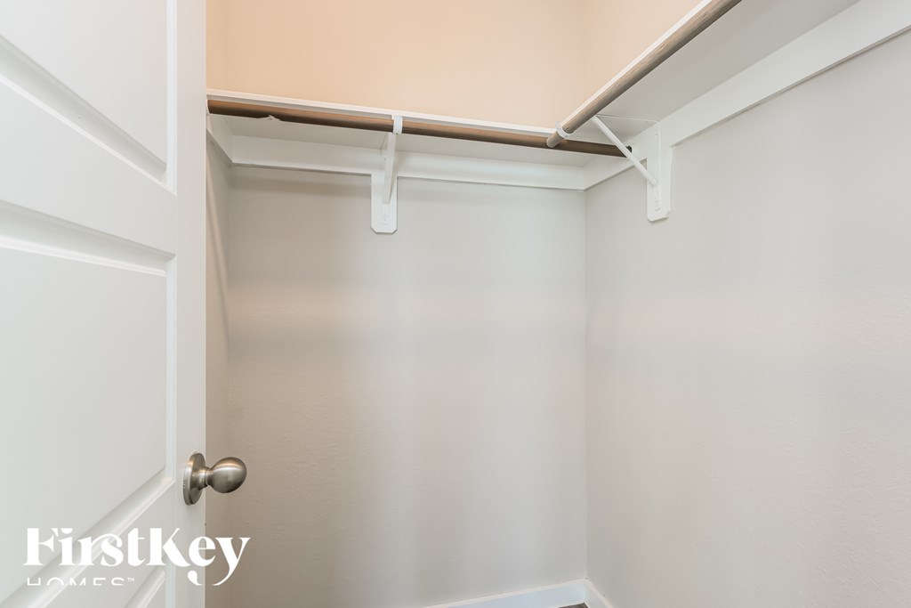 A white door with a silver handle is open to a small, empty room with white walls.