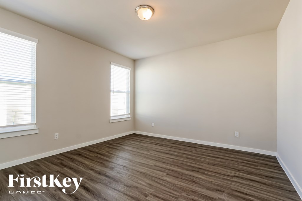 A room with wooden flooring and a window with blinds.
