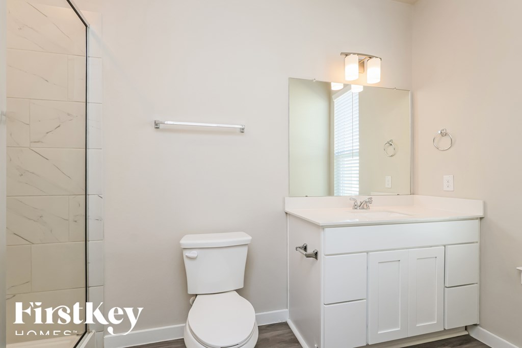 A white toilet in a bathroom with a white cabinet and a mirror above it.