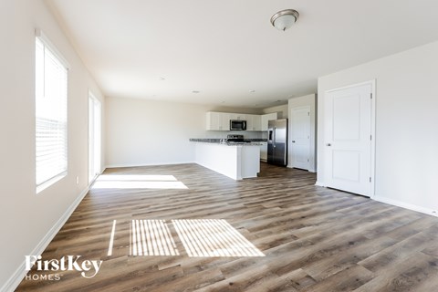 A spacious kitchen and living room with wooden floors and white walls.