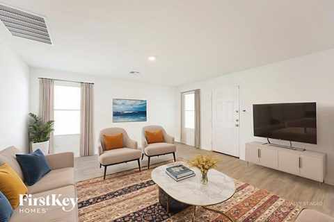 A living room with a sofa, chairs, a coffee table, and a television.