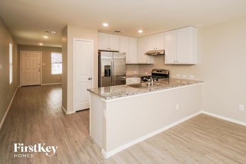 A kitchen with a white island and wooden floors.