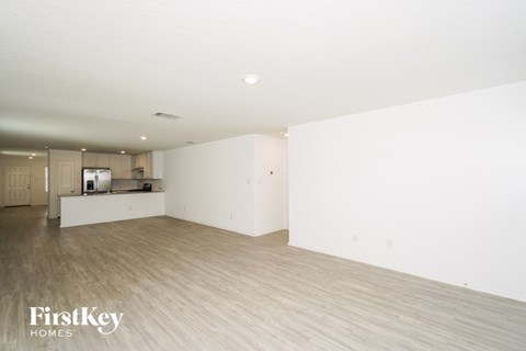 A spacious, empty room with wooden flooring and white walls.