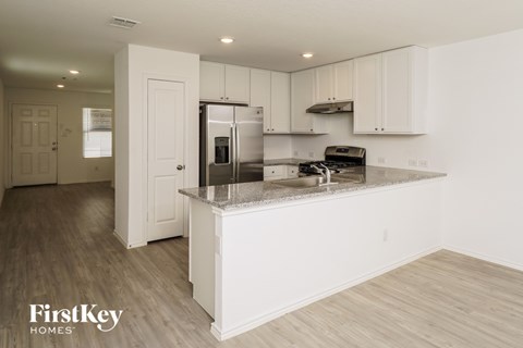 A kitchen with white cabinets and a wooden floor.