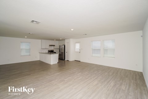 A spacious, empty room with wooden flooring and white walls.