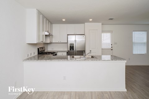 A kitchen with white cabinets and a granite countertop.