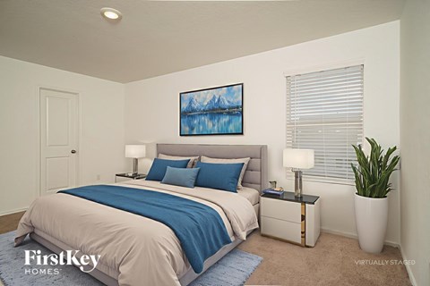 A bedroom with a bed, nightstand, and a painting on the wall.