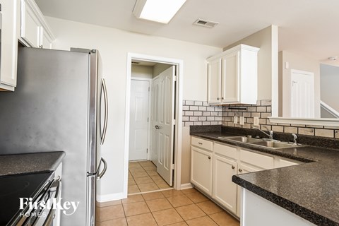 A kitchen with a black granite countertop and white cabinets.