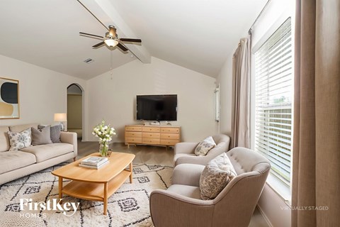 A living room with a television, a couch, a coffee table, and a ceiling fan.