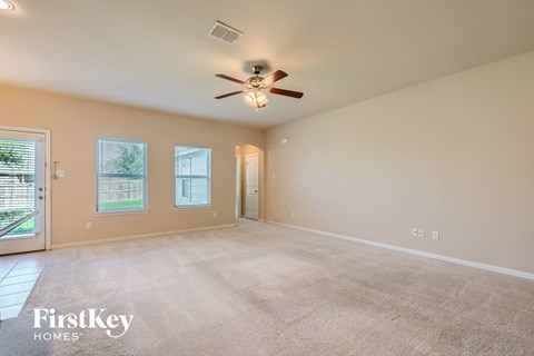 A spacious room with a ceiling fan and carpeted floor.