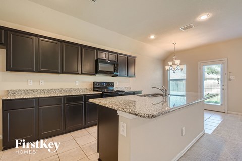 A kitchen with a granite countertop and a microwave above it.