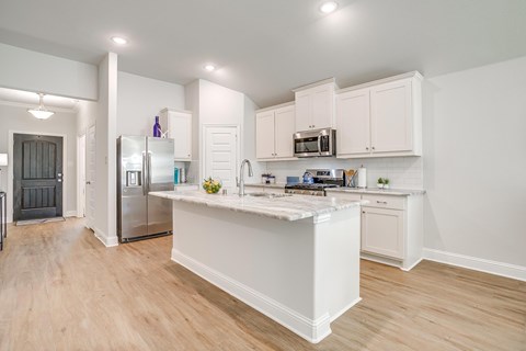 A kitchen with white cabinets and a white island.