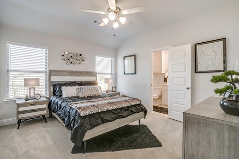 A bedroom with a large bed and a ceiling fan.