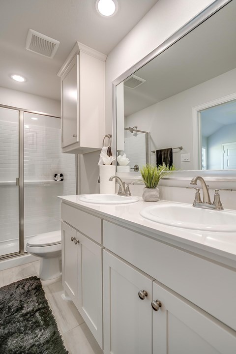 A white bathroom with a toilet, sink, and mirror.