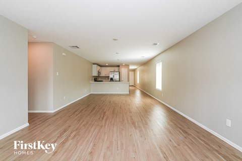 A spacious room with wooden floors and a kitchen area in the distance.