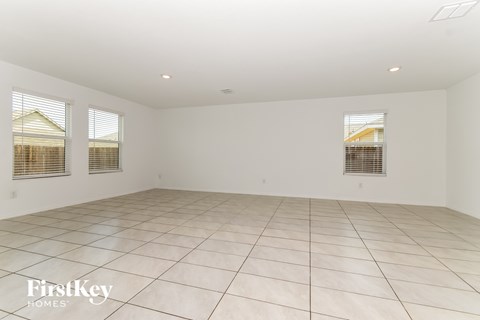 A spacious empty room with tiled flooring and three windows.