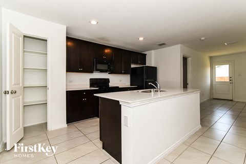A kitchen with a black fridge and white countertops.