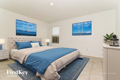 A bedroom with a large bed and two paintings on the wall.