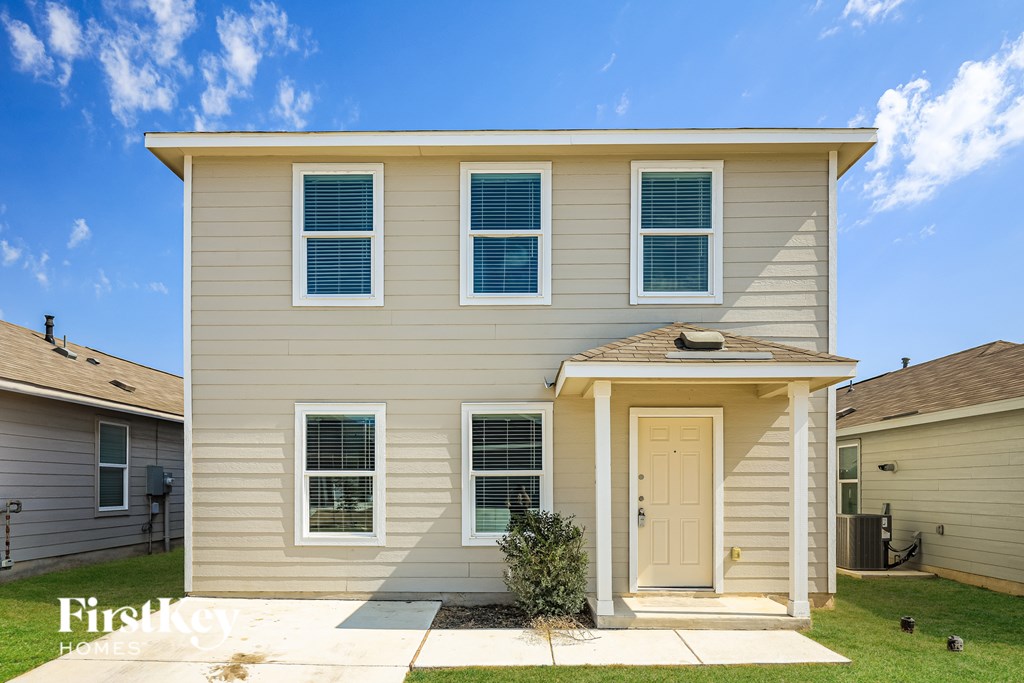 A beige house with a white door and windows.