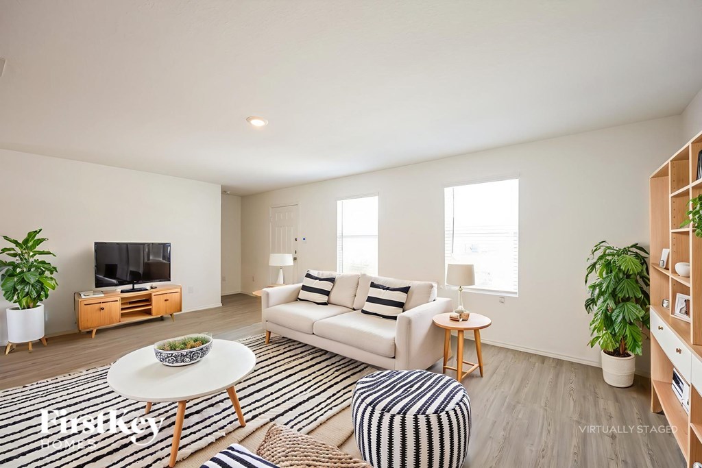 A living room with a white couch, a coffee table, and a television.