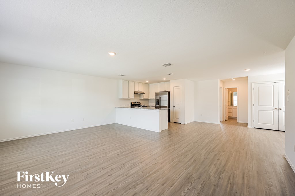 A spacious room with wooden flooring and a kitchenette in the corner.