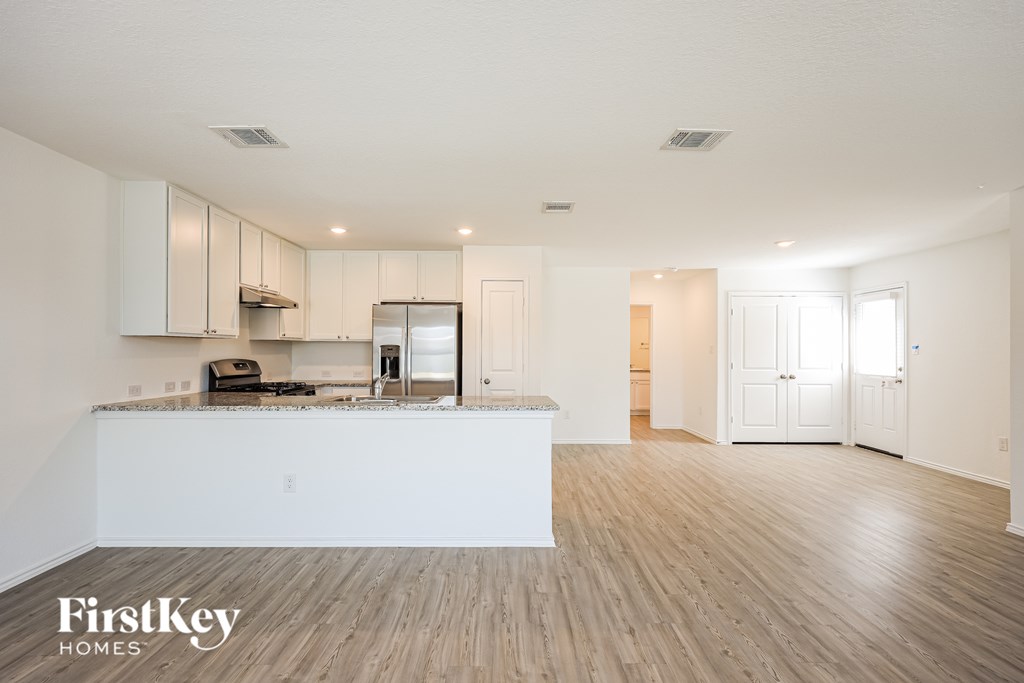 A spacious kitchen with wooden floors and white walls.