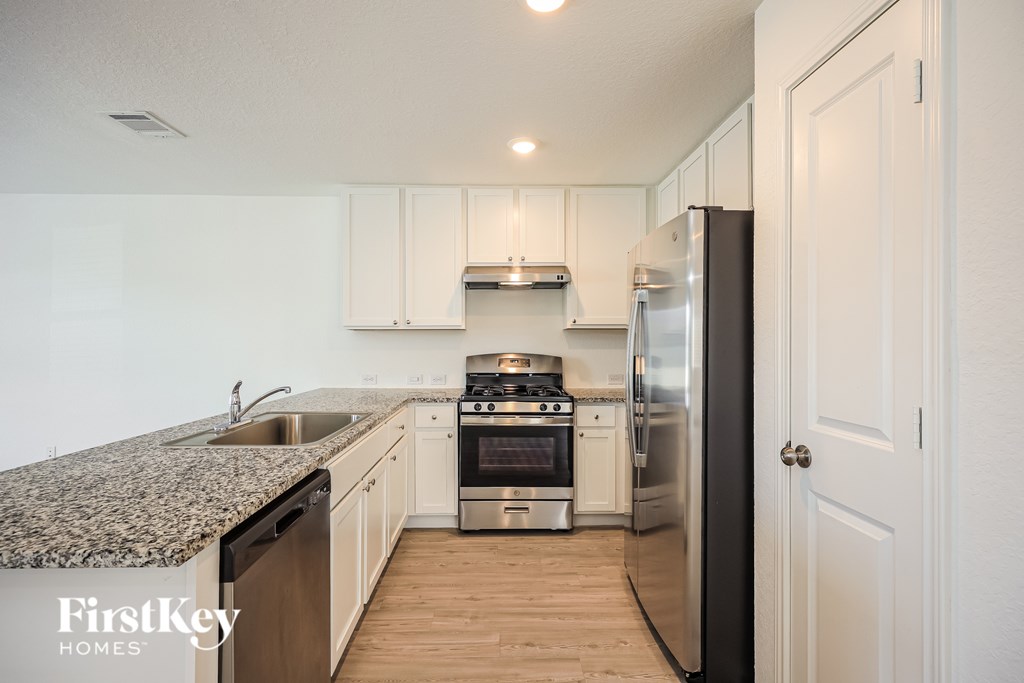 A kitchen with a granite counter top and stainless steel appliances.