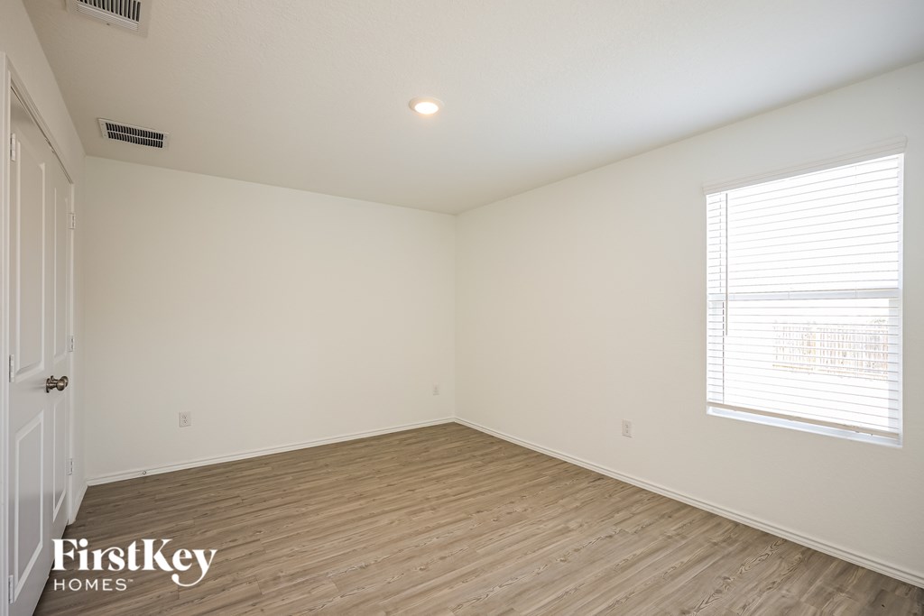 A room with wooden flooring and a window with blinds.