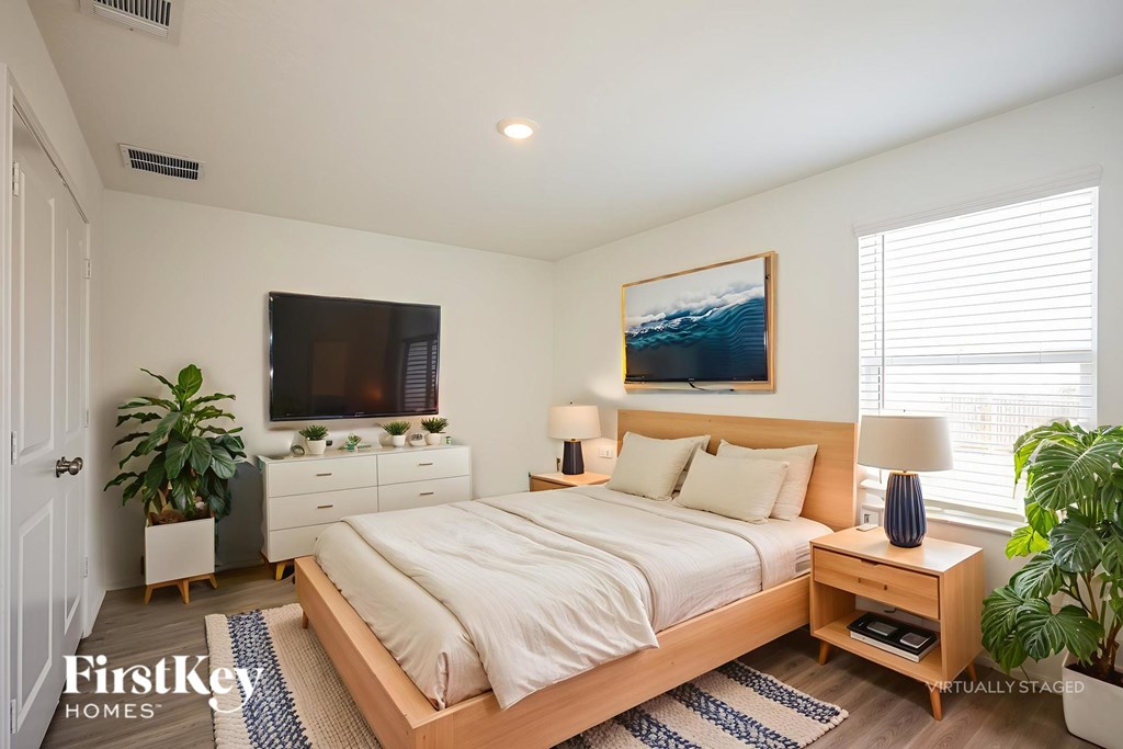 A bedroom with a bed, nightstand, and a painting on the wall.