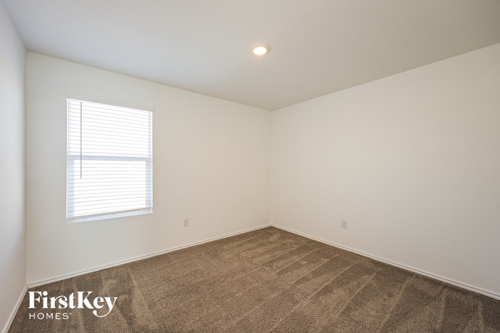 A room with a carpeted floor and a window with blinds.