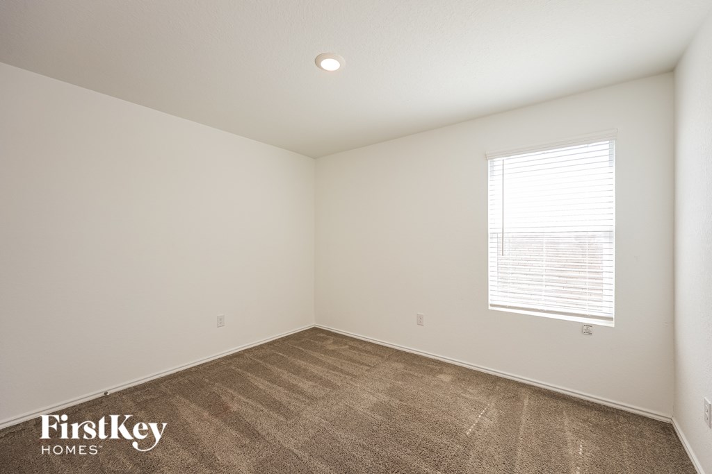 A room with a carpeted floor and a window with blinds.